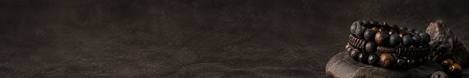 Editorial still life of dark stone, cord, and natural material forms for the bracelet collection