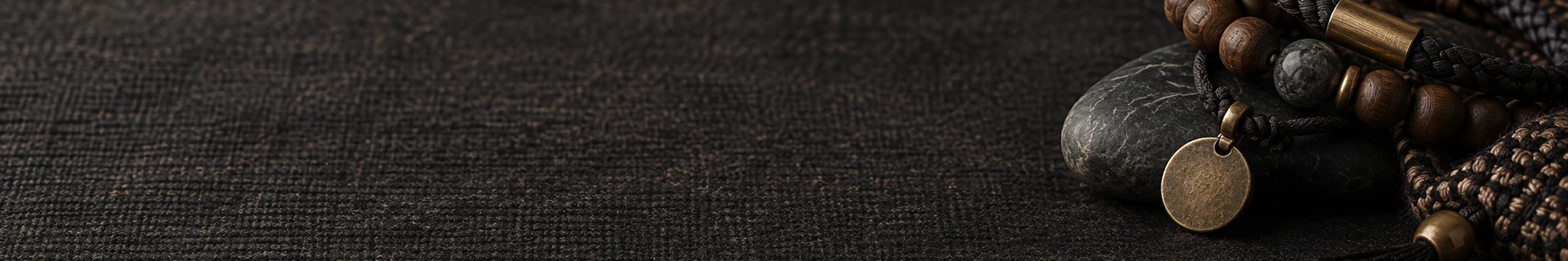 Editorial still life combining dark cord, wood, stone, brushed metal, and woven textile