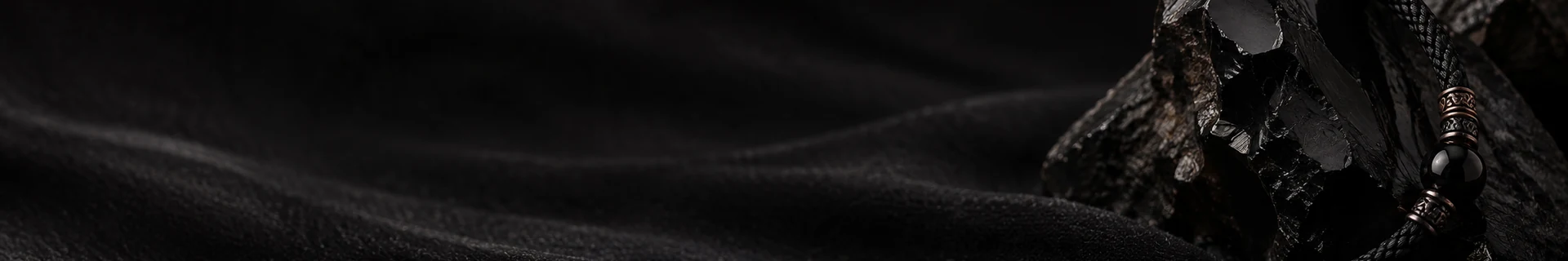 Editorial still life of dark mineral, architectural shadow, and a defined cord boundary