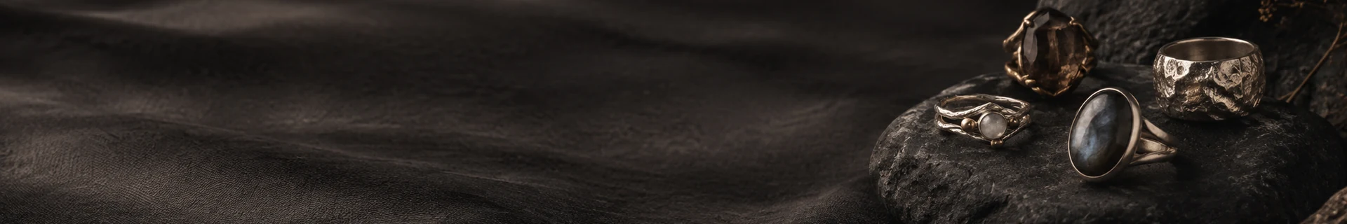 Editorial close study of round stone and metal ring forms on dark slate