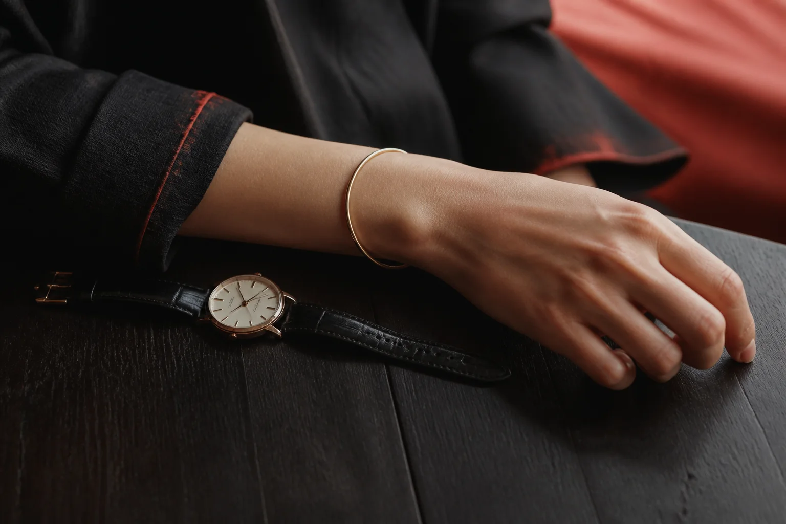 A person resting one hand on a table while a simple circular bangle catches a small line of light