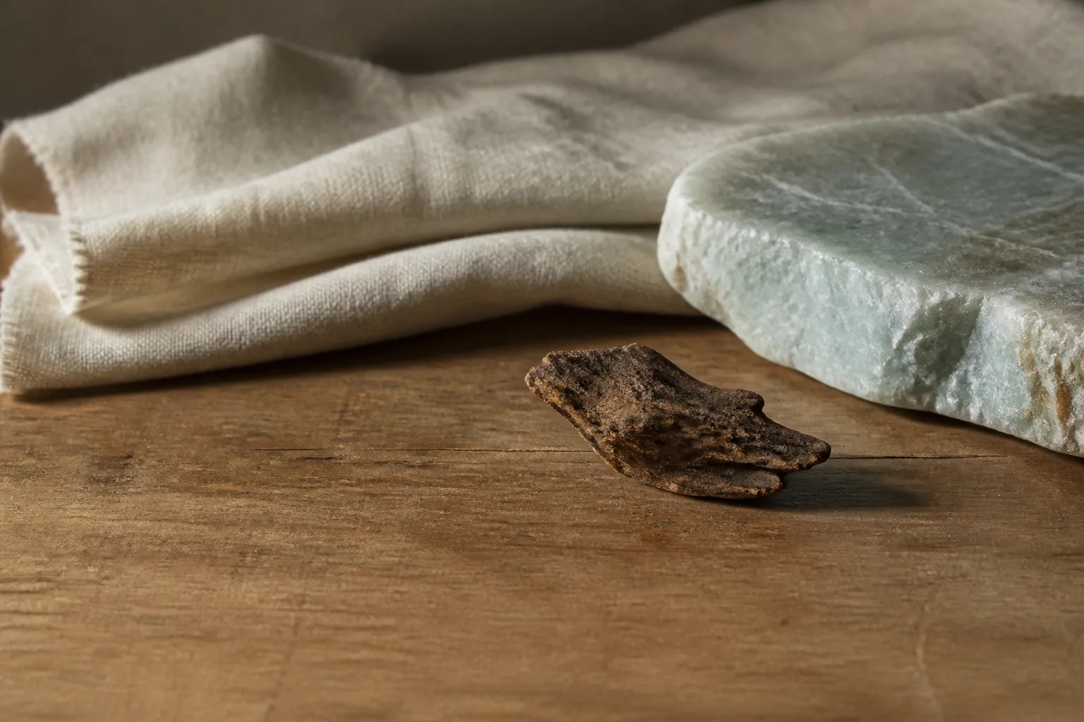 A small piece of dark agarwood and pale stone arranged on a quiet worktable