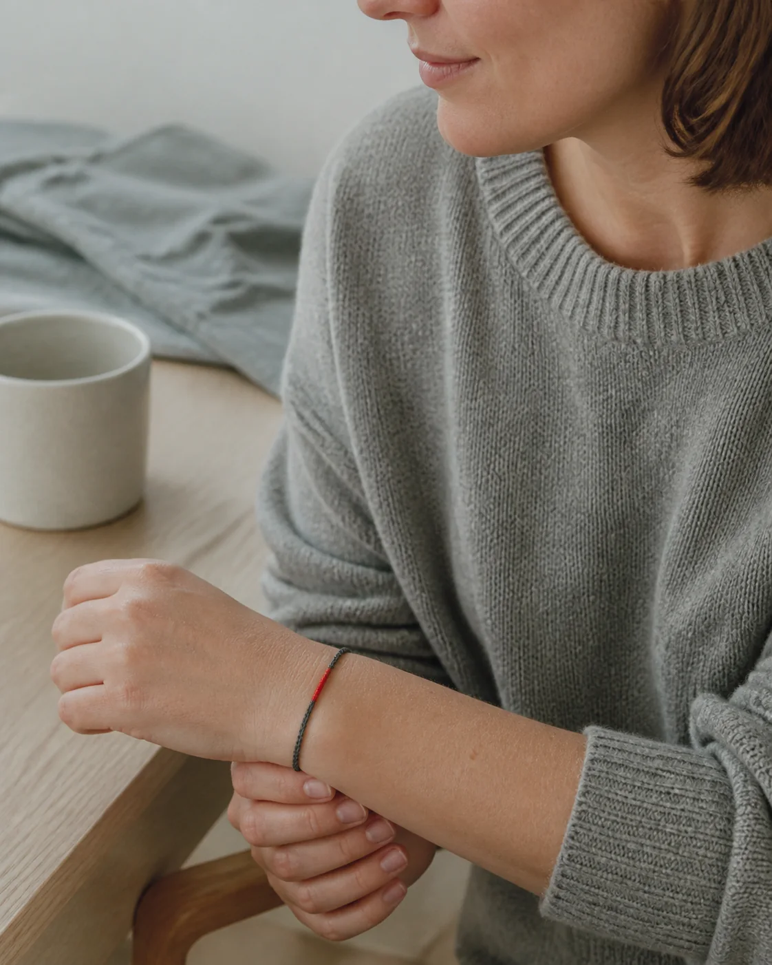 Illustrative scene of an adult wearer naturally wearing a simple handmade cord bracelet in a quiet home setting